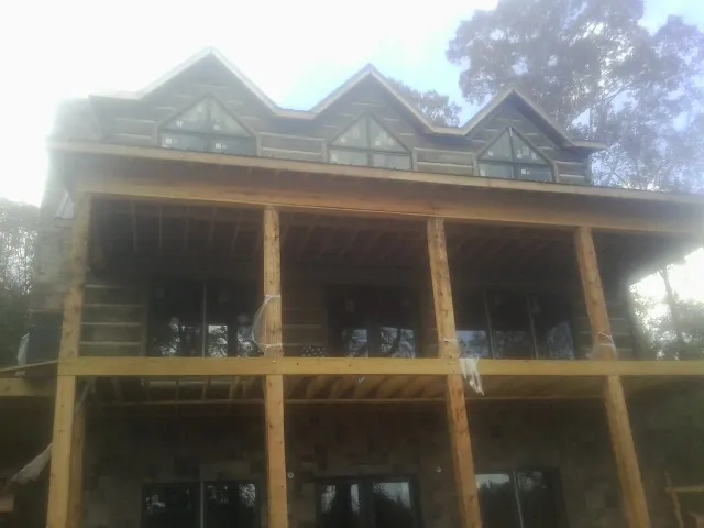 Dormers and porch framing on a large log home under construction — Roof Coating work by our crew in Wilton